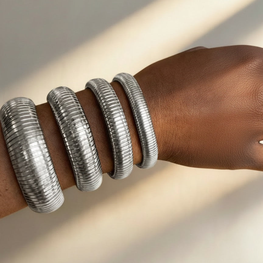 Silver bangles on a wrist with a neutral background