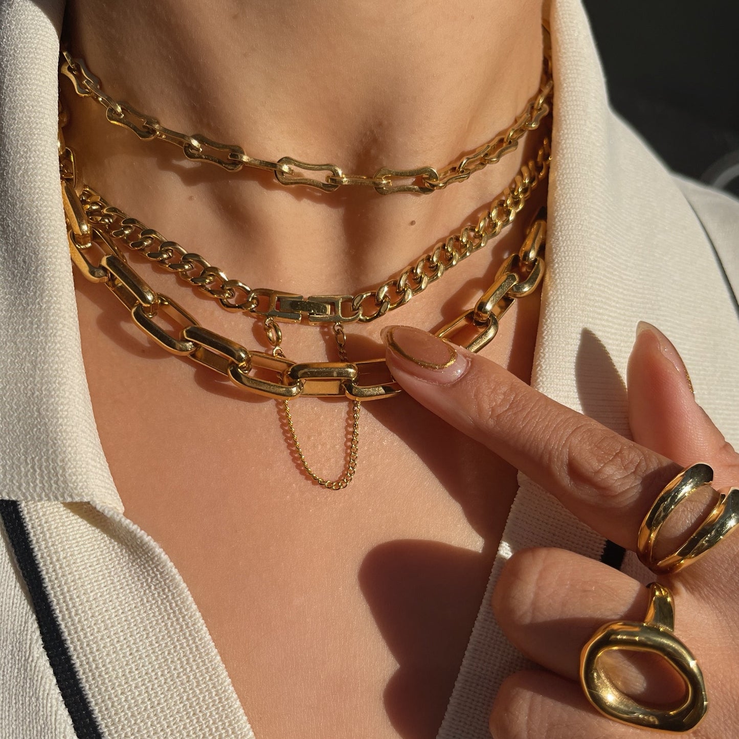 Close-up of a person wearing gold tarnish free necklaces and rings on a blurred background