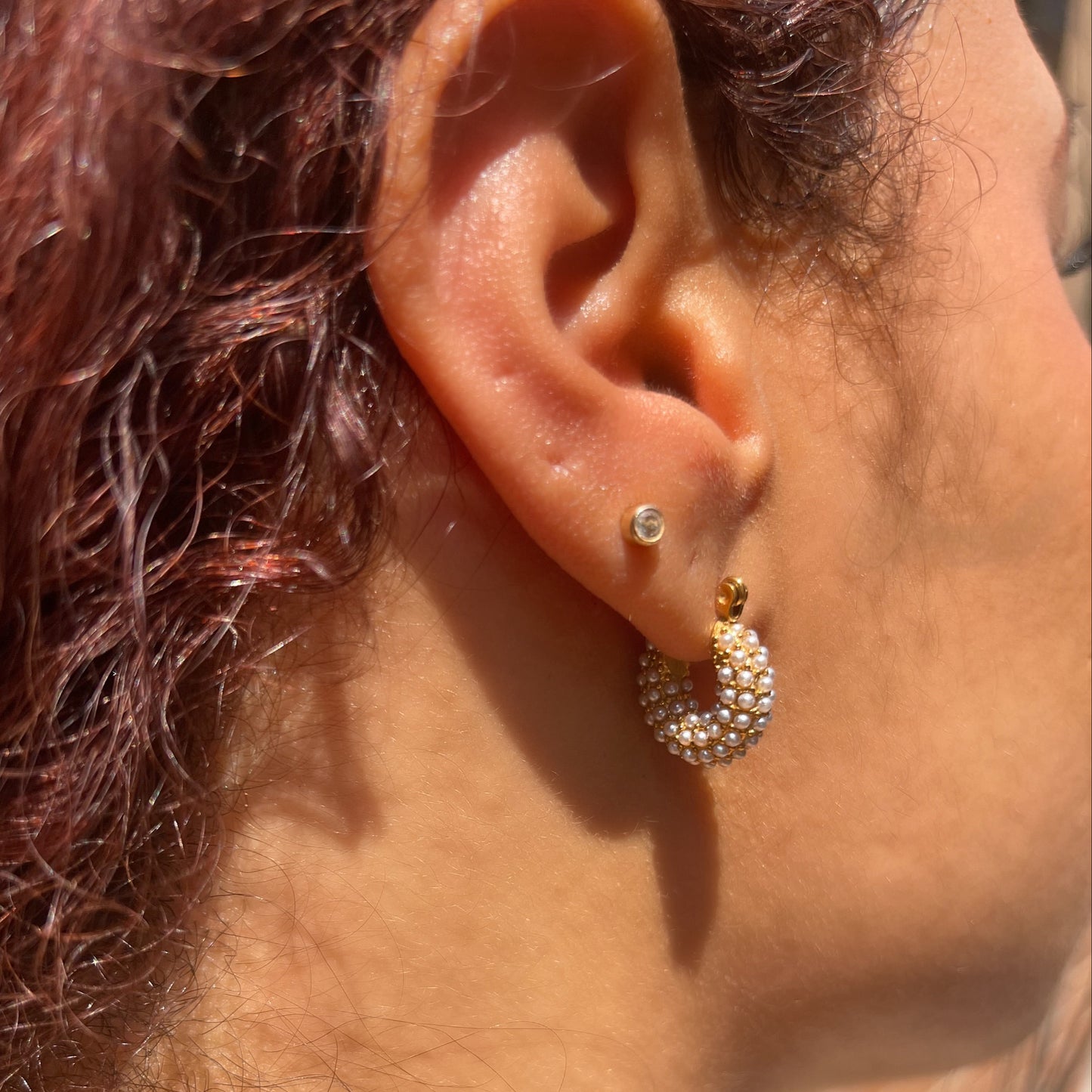 Close-up of an ear wearing pearl gold earrings.