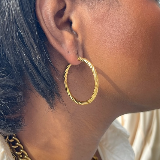 Close-up of a person wearing a gold hoop earring and necklace.