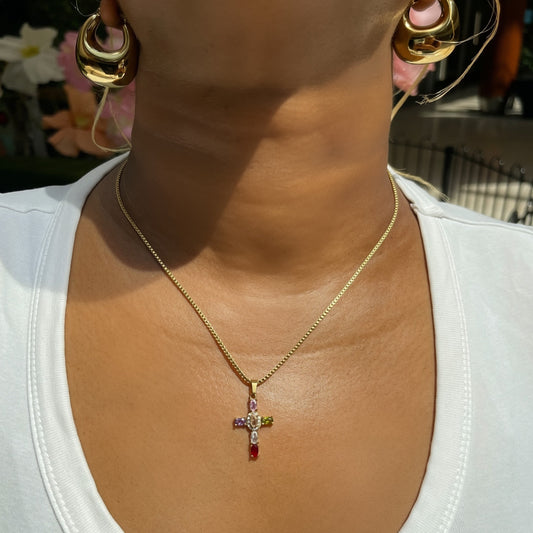 Gold necklace with a cross pendant worn by a person