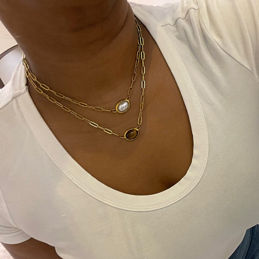Close-up of a person wearing a white top and gold necklaces.