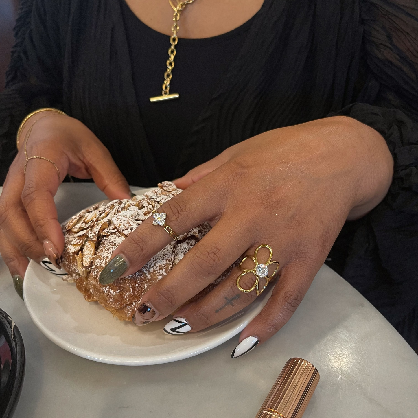 Person holding a pastry with jewelry on a table