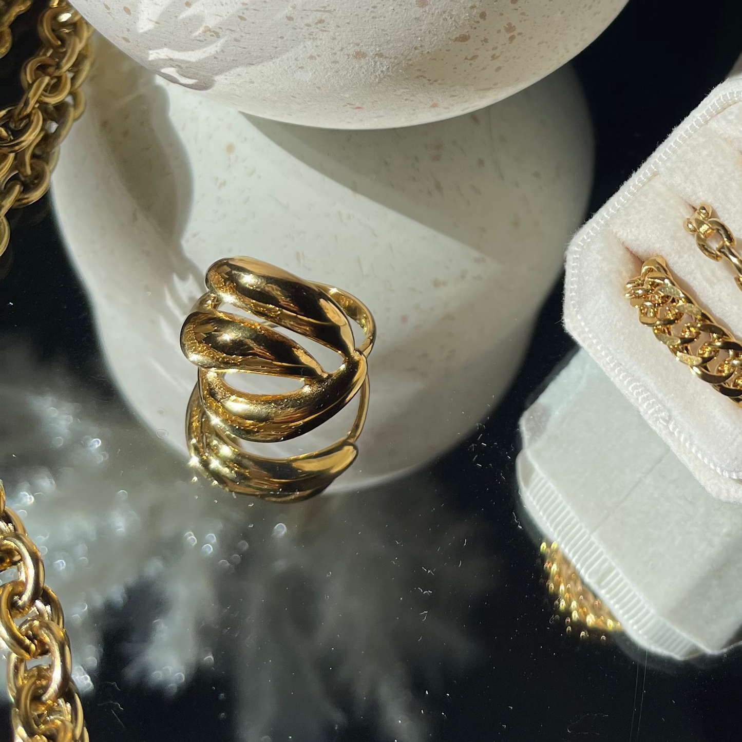Gold rings on a white stone surface with a decorative black background