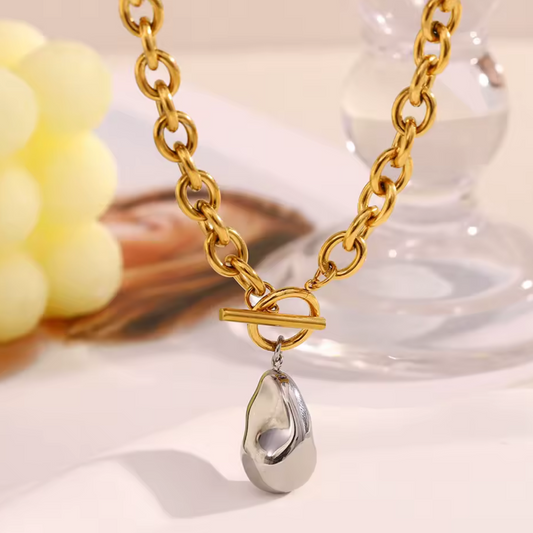Gold and silver necklace on a white surface with a blurred background