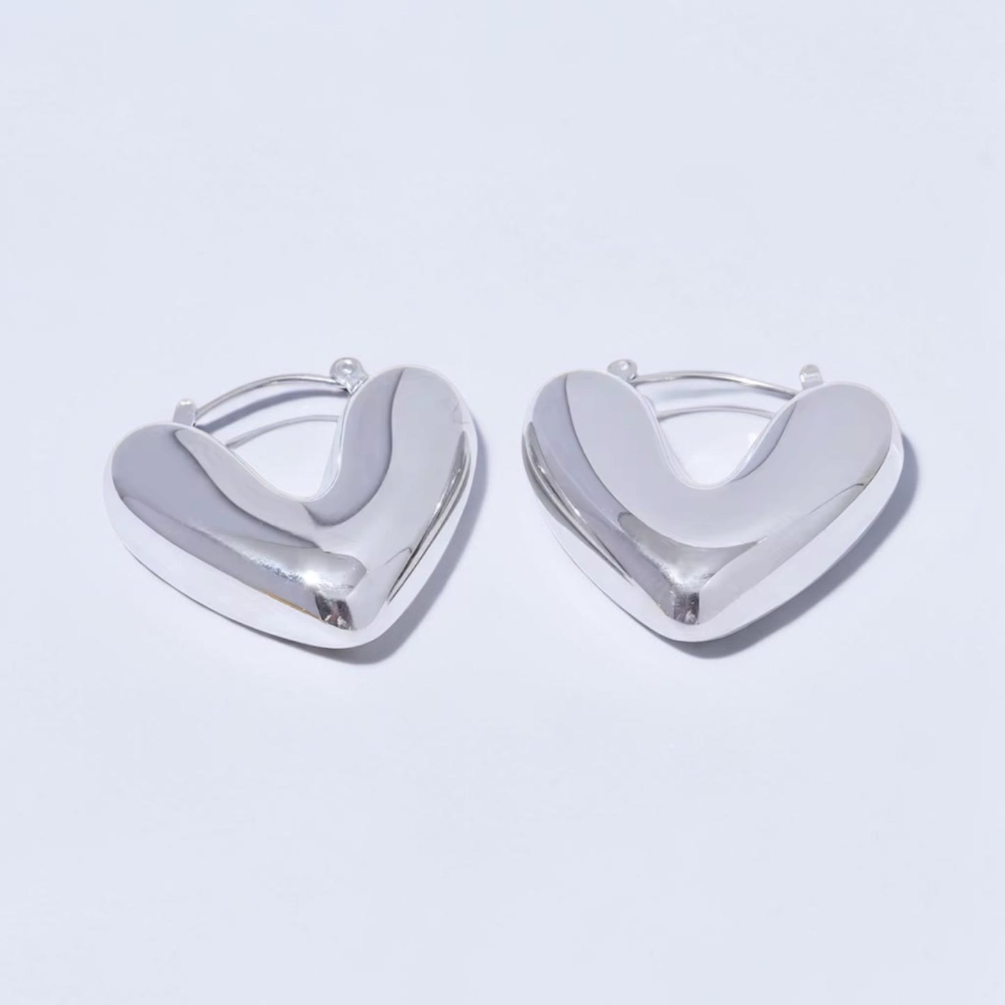 Silver heart-shaped earrings on a light gray background