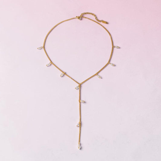 Gold necklace with small pearls on a light pink background