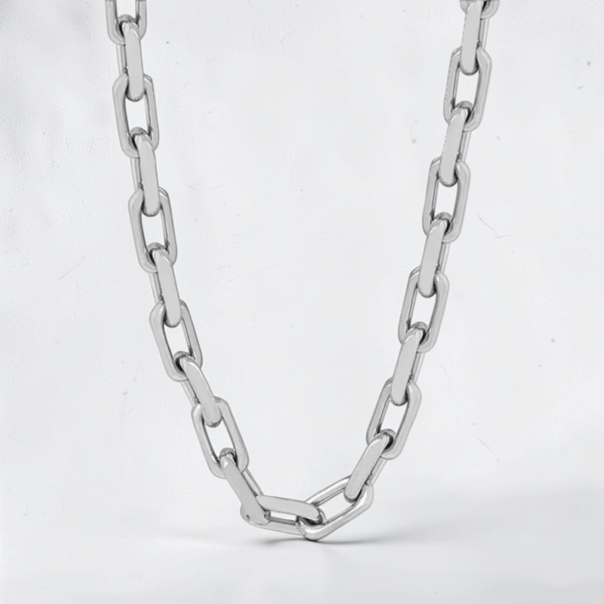 A silver-toned metal chain necklace with elongated oval links, photographed against a plain light gray background.