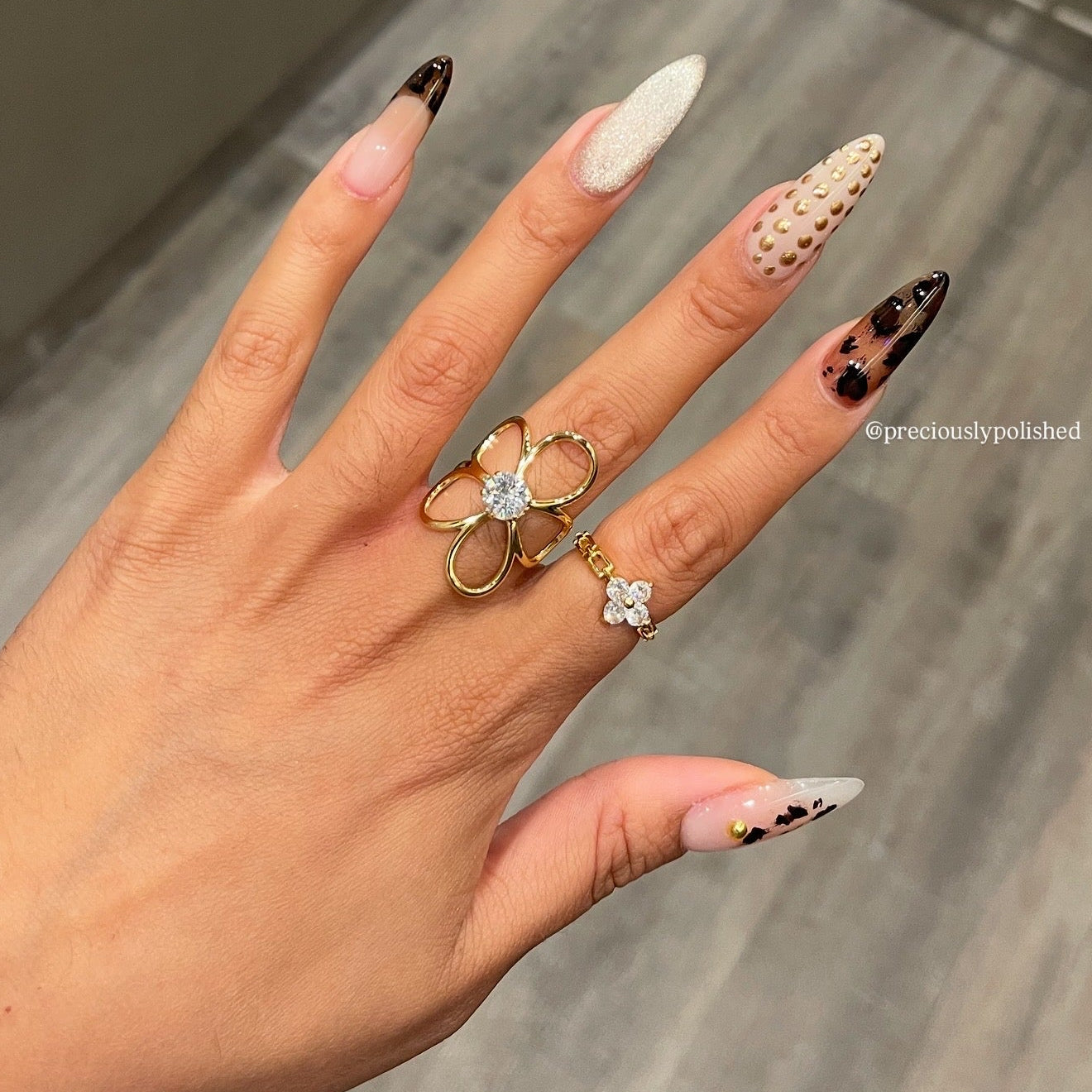 Hand with decorative nails and rings on a neutral background