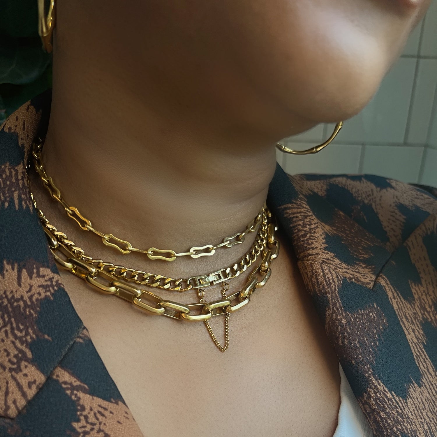 Close-up of a person wearing gold chain necklaces with a patterned garment.