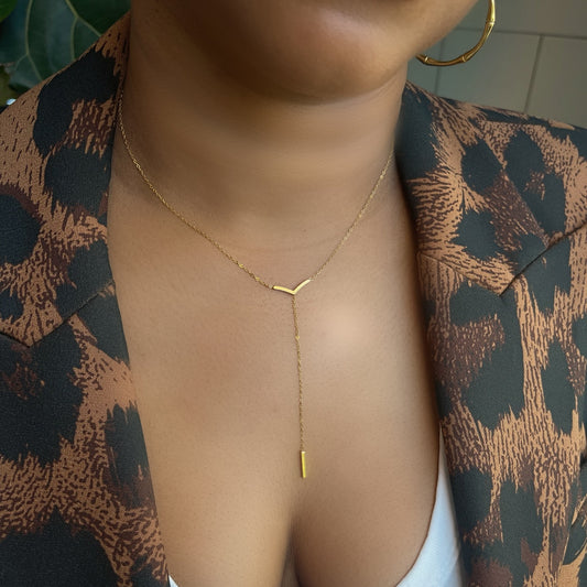 Person wearing a gold necklace with a patterned garment