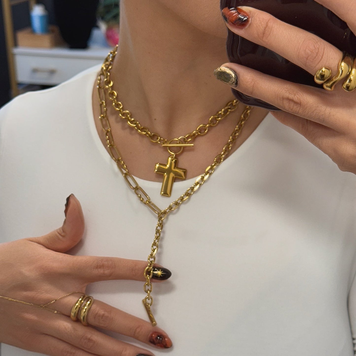 waterproof Gold necklace with a cross pendant worn by a person, with a blurred background.