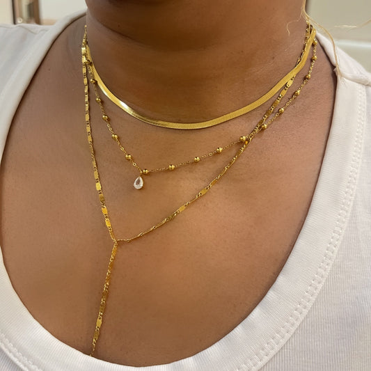 Close-up of a person wearing gold necklaces on a plain background