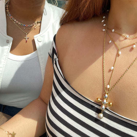 Two people wearing layered necklaces with a focus on one person's necklace.