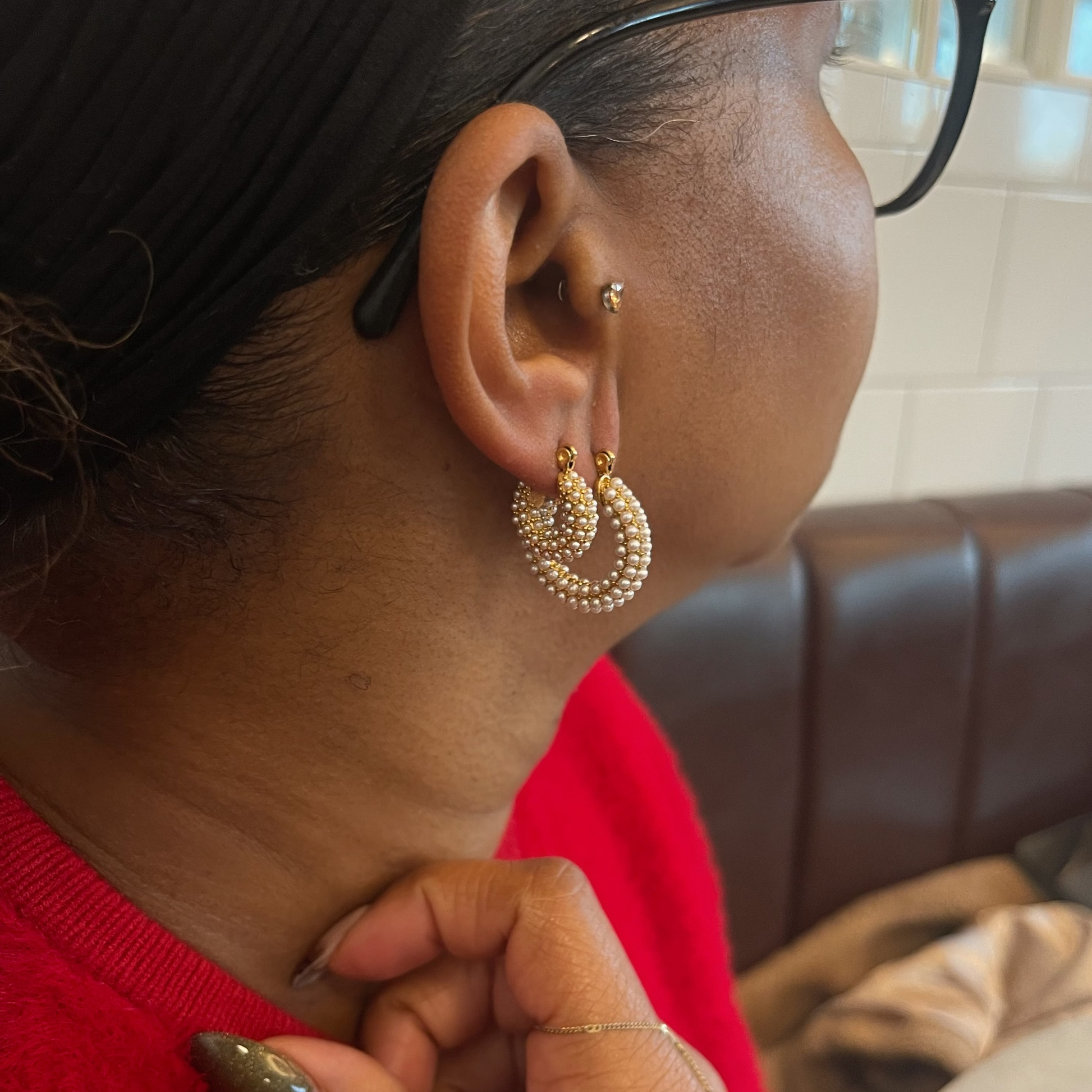 Close-up of a person wearing gold hoop earrings with a blurred background
