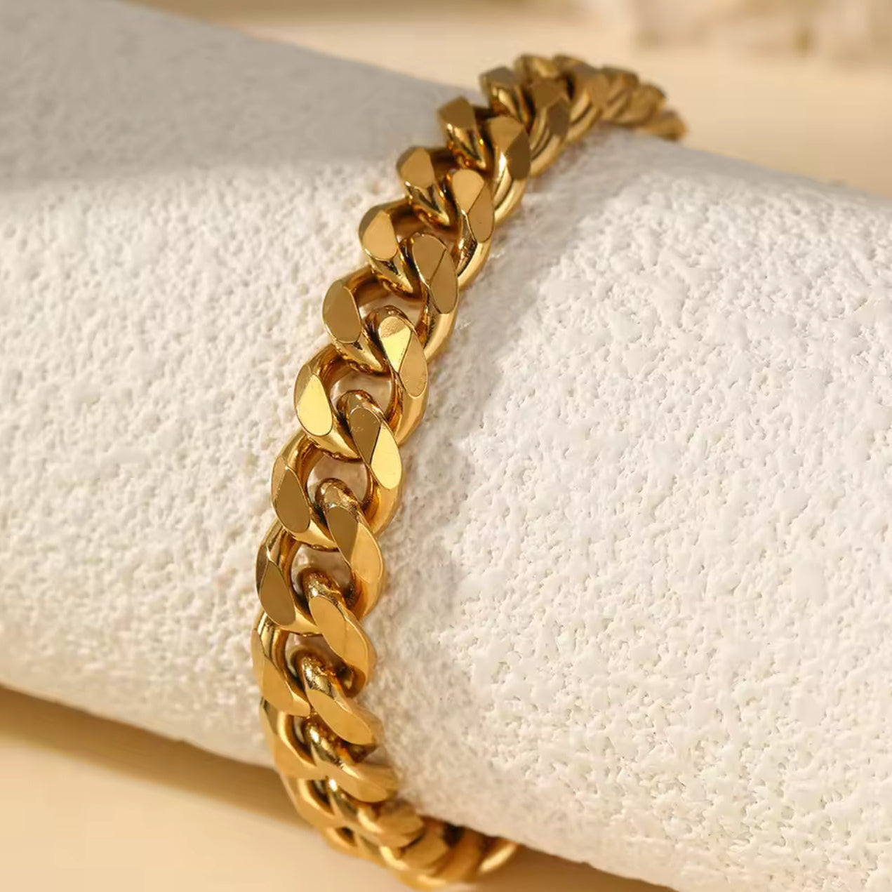 Gold chain anklet on a textured white surface