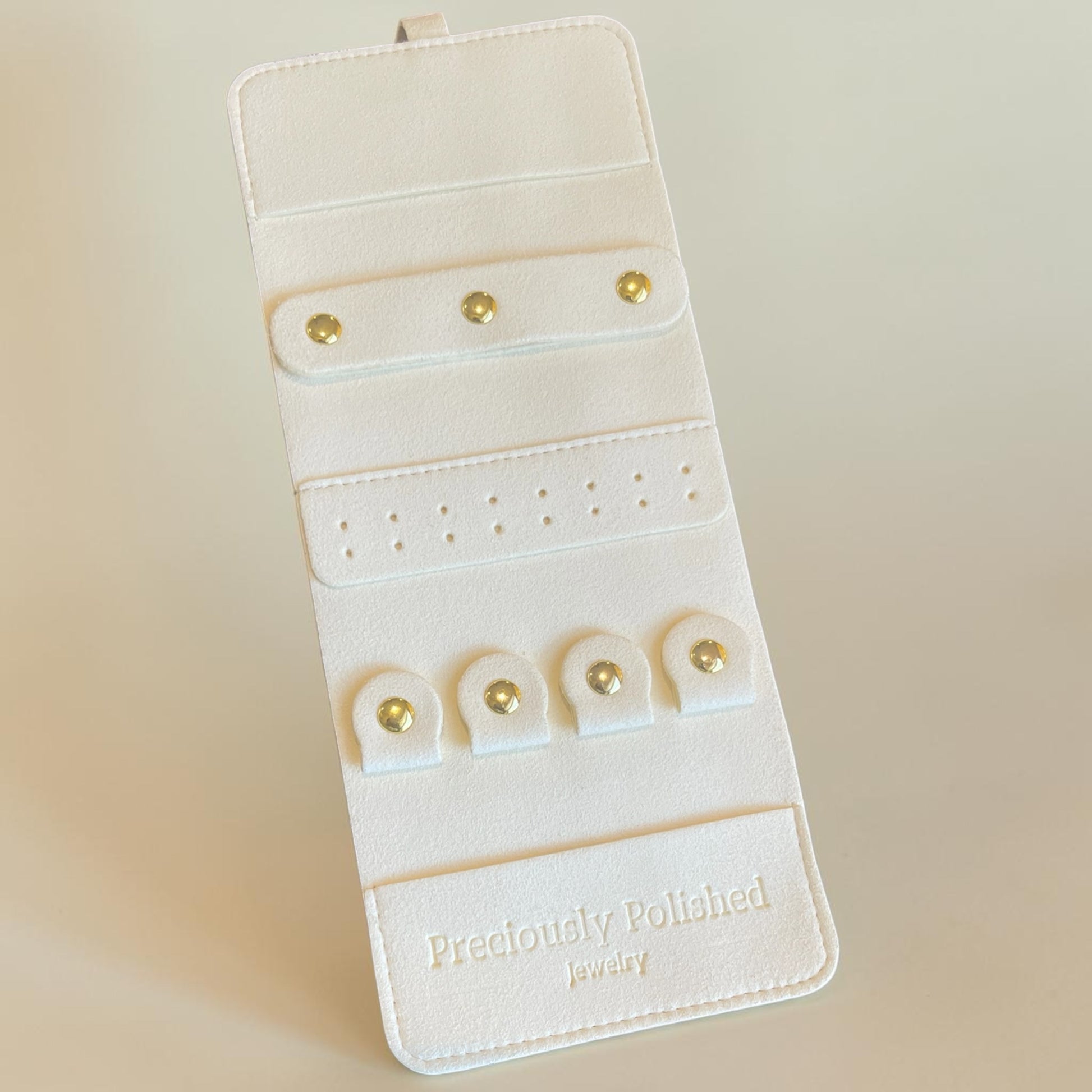 White jewelry organizer with gold earrings on a beige background