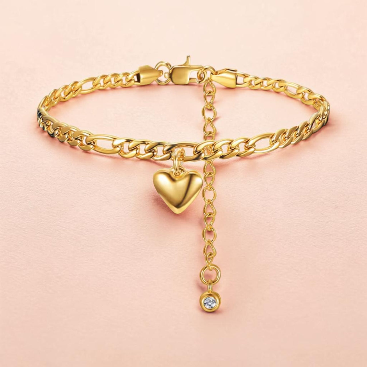 Gold anklet with a heart-shaped charm on a pink background
