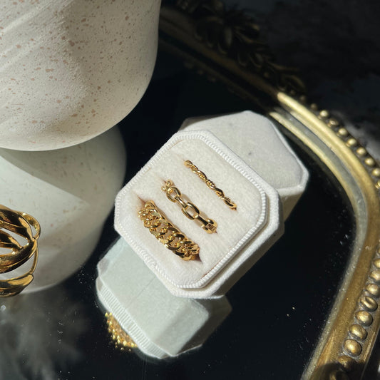 Gold rings on a white stone surface with a decorative mirror in the background