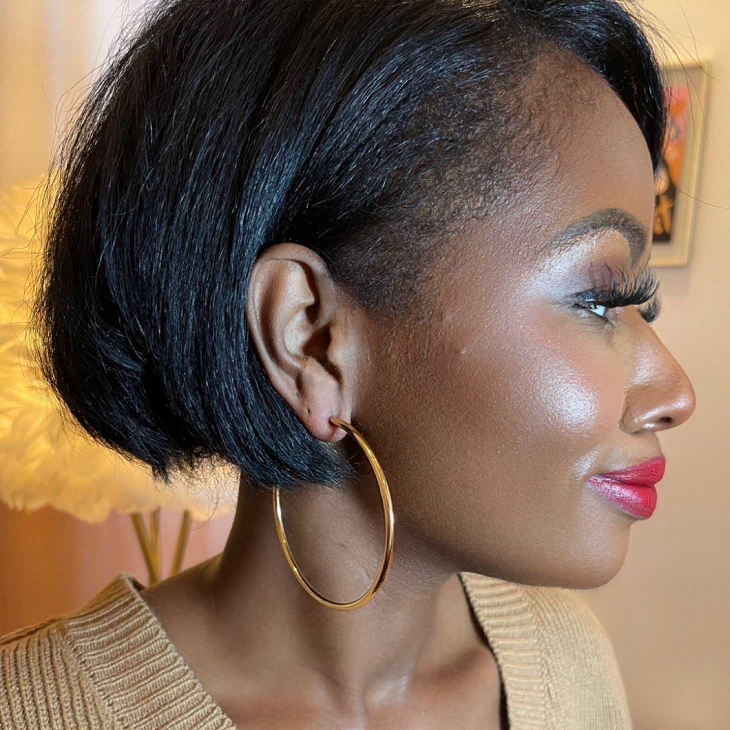 Woman with styled hair wearing a gold earring indoors