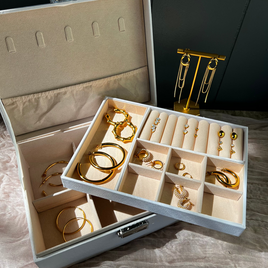 Open jewelry box with gold earrings on a textured surface
