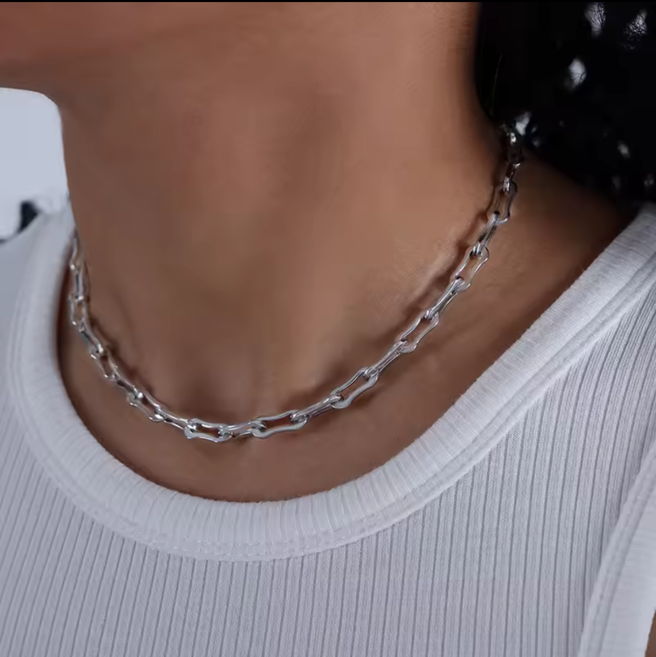 Close-up of a person wearing a silver chain necklace.