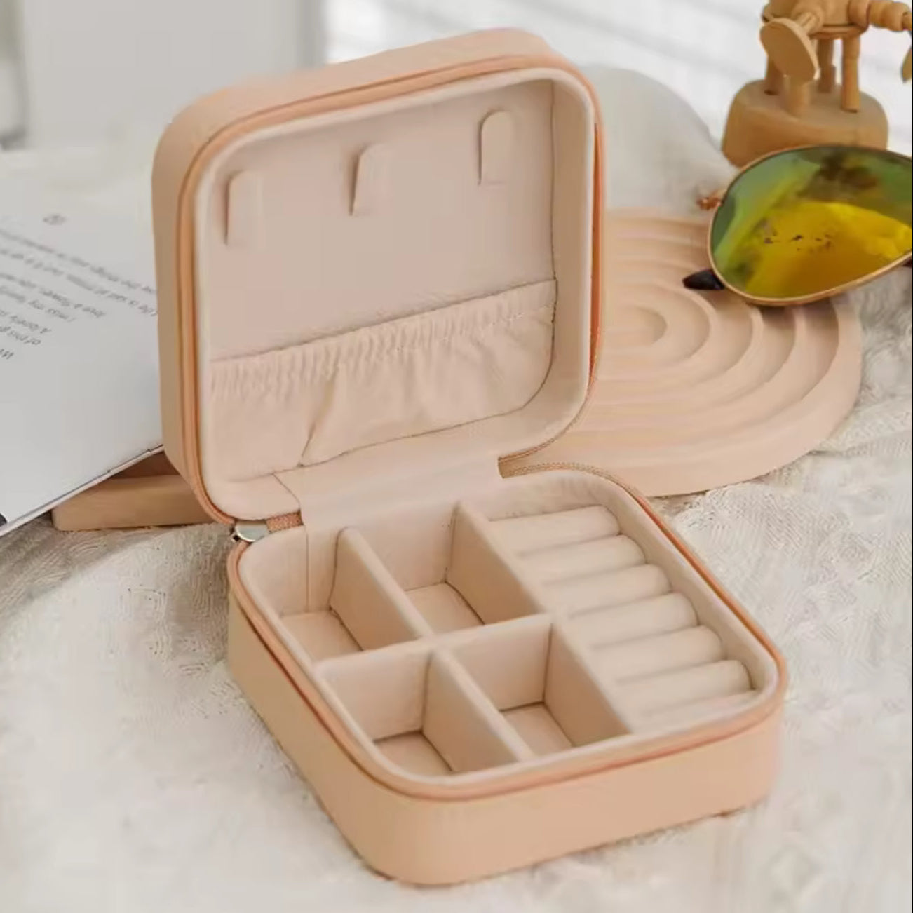 Beige jewelry case with compartments on a light surface