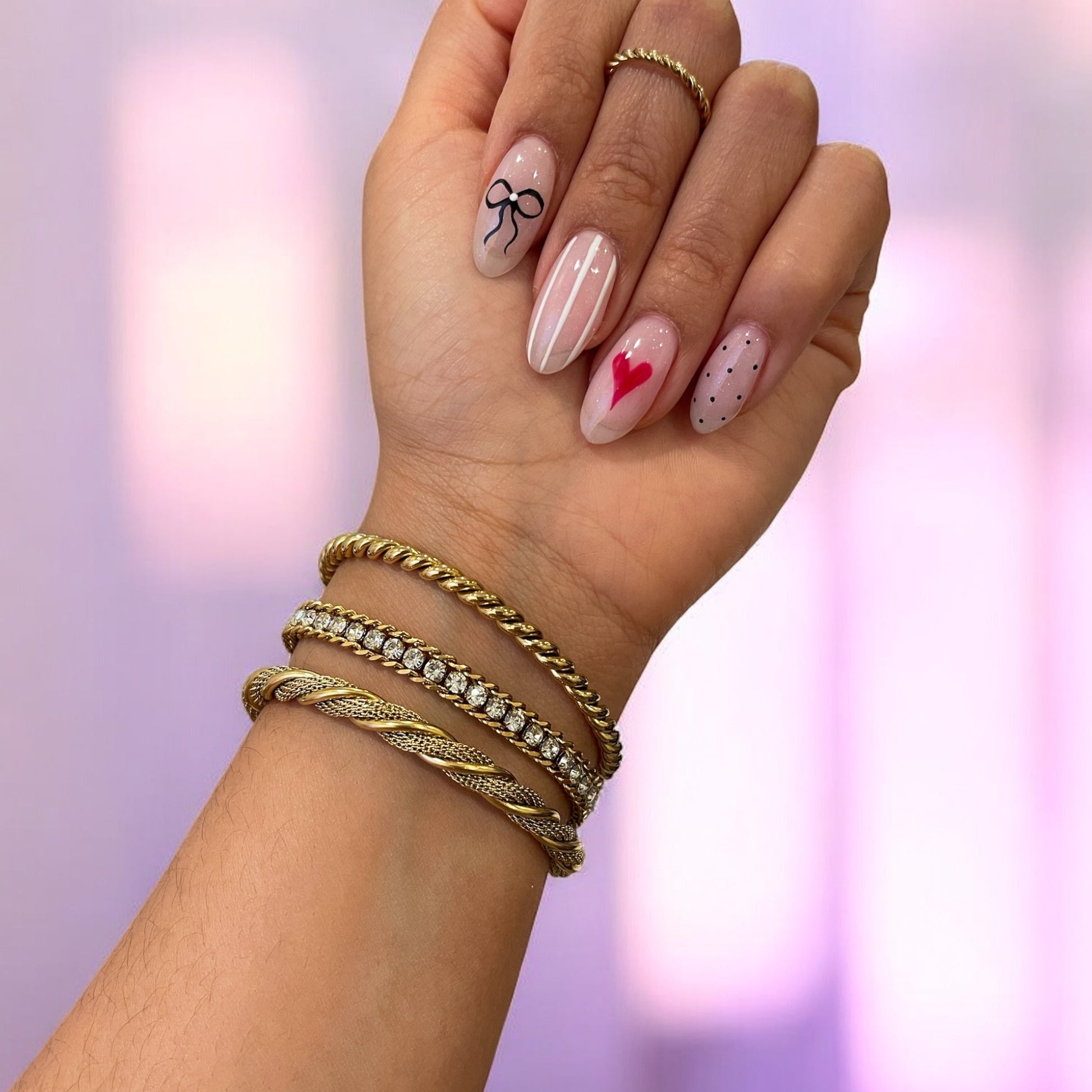 Hand with gold bracelets and decorated nails against a blurred background