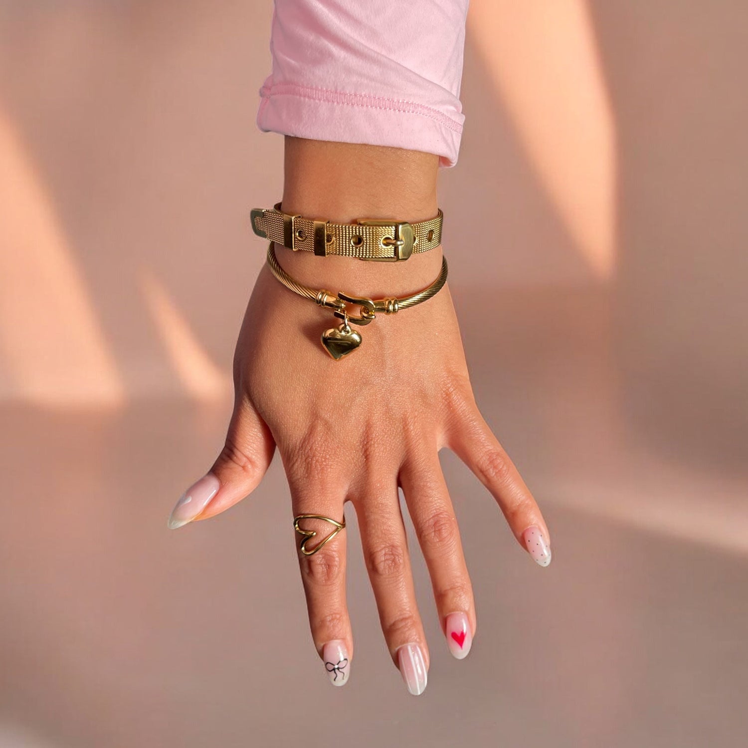 Hand wearing gold bracelets and rings with a blurred background