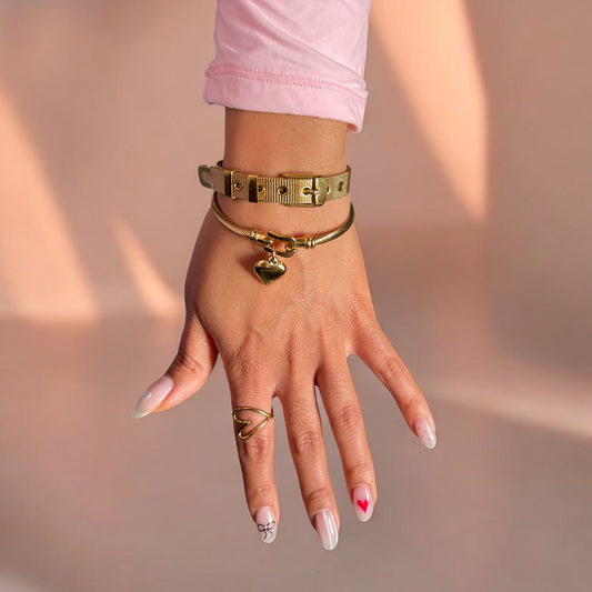 Hand wearing gold bracelets and rings with a blurred background