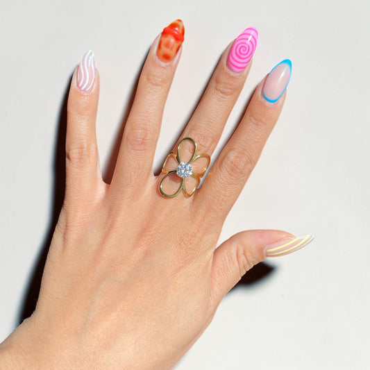 Hand wearing a gold ring with a diamond on a light background