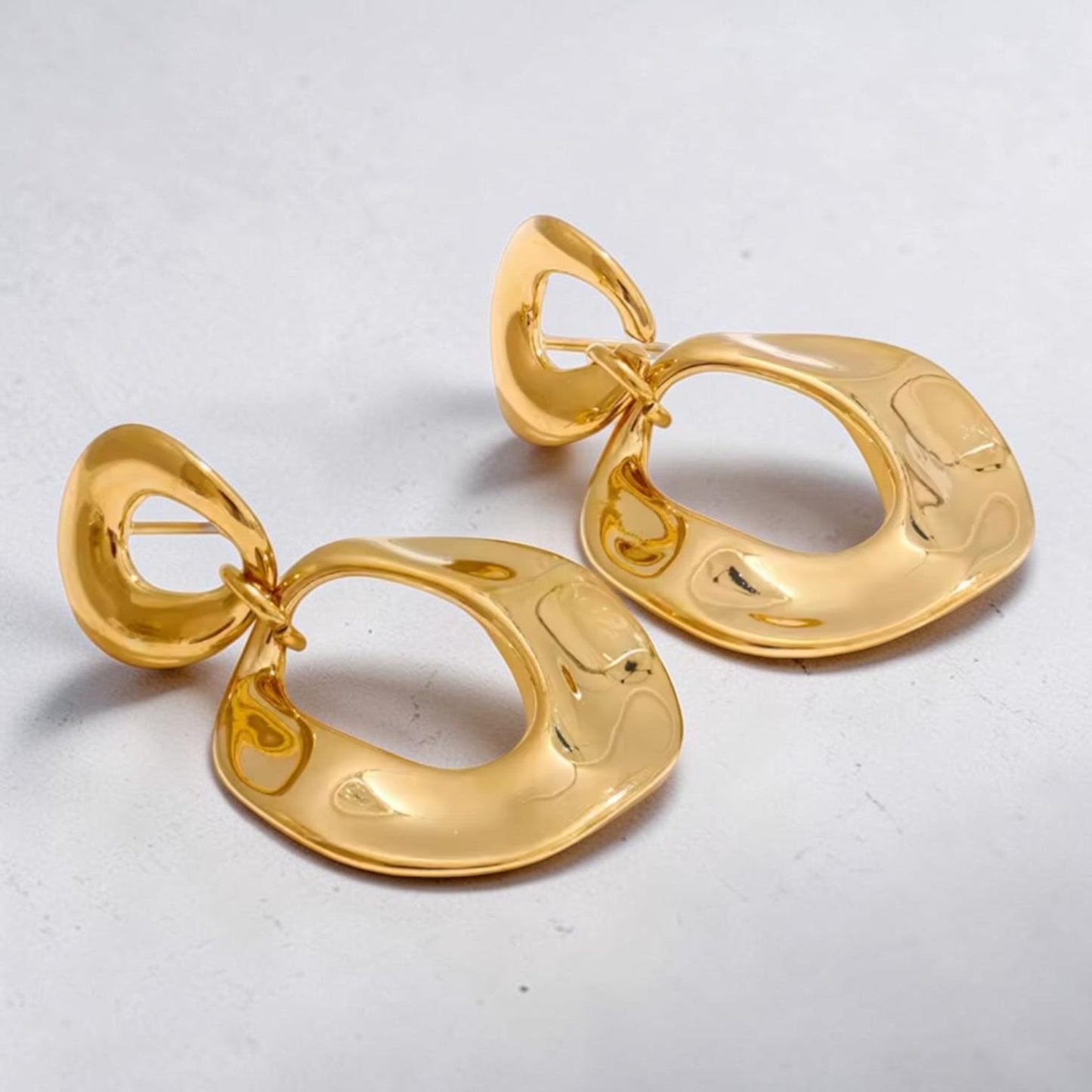 Pair of gold earrings on a light gray background